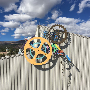 Solar powered kinetic metal sculpture mounted at roofline of building